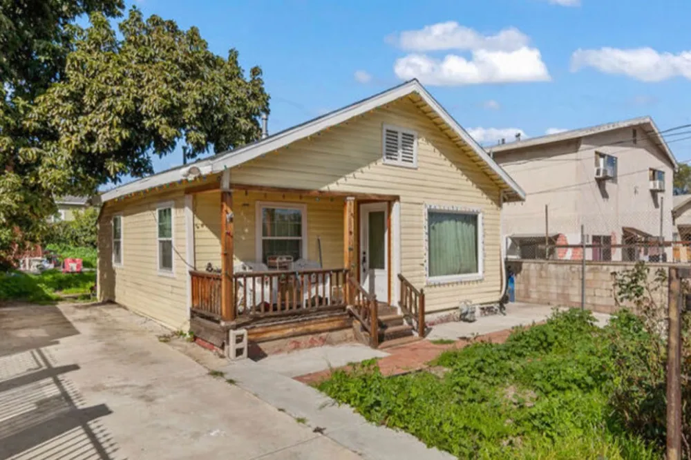 House before: faded yellow exterior with overgrown yard
