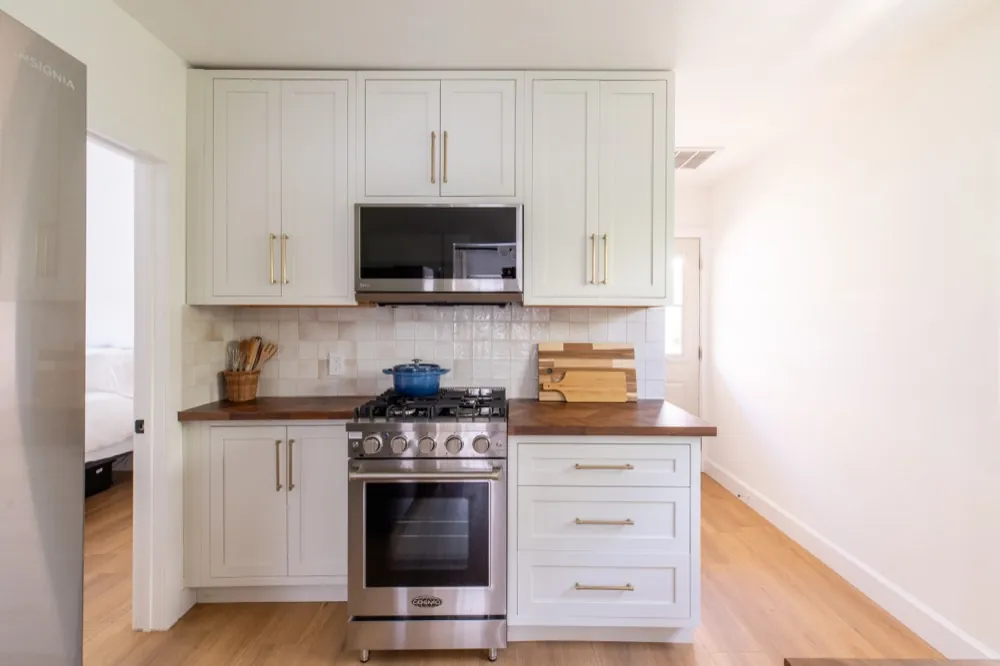 Kitchen after: white shaker cabinets, butcher block counters, tile backsplash