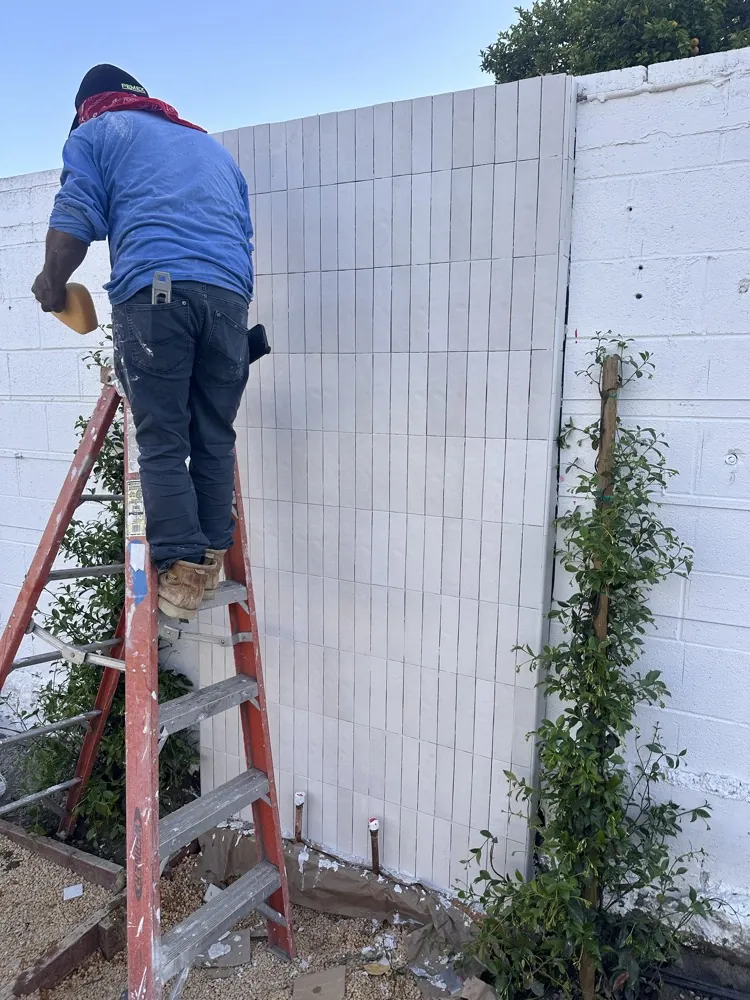 Outdoor shower during construction: tile being set on the wall