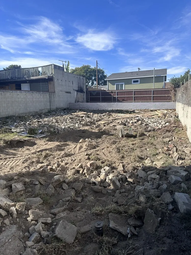 Backyard before: bare lot covered in broken concrete rubble