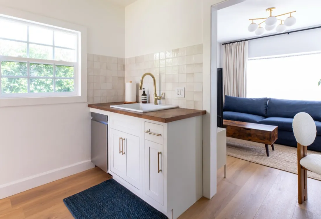 Kitchen sink area with brass faucet and tile backsplash